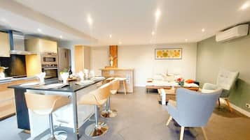 Une cuisine moderne avec un coin bar, des chaises de salle à manger, un canapé et une table basse.
