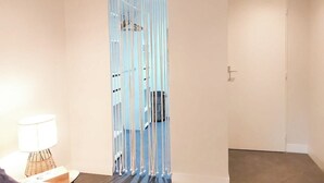Una stanza con una grande finestra, una porta e una lampada su un comodino.