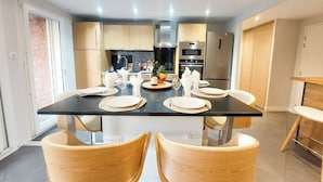 Una cucina moderna con isola centrale, sedie in legno e tavolo da pranzo per quattro persone.