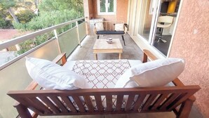 Un balcone con una sedia in legno, un tavolino e un divano con dei cuscini.