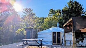 A yurt with a wooden deck, a small wooden structure, and a covered area. - Ace Mongolian Yurt (Saint Anns)