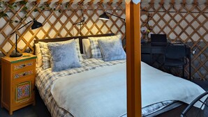 A yurt interior with a bed, desk, and a hanging light fixture. - Ace Mongolian Yurt (Saint Anns)