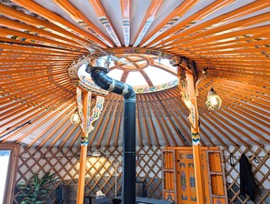 A traditional yurt with a circular wooden frame, a central black pole, and a patterned ceiling. - Ace Mongolian Yurt (Saint Anns)