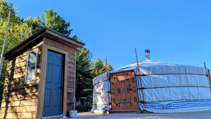 A wooden cabin with a blue door and a yurt with decorative patterns. - Ace Mongolian Yurt (Saint Anns)