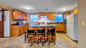 A kitchen with wooden cabinets, a central island, bar stools, and a refrigerator. - Sunset Harbor Retreat,3 bed, 2 bath w/ private launch and dock in charming Isle (Isle)