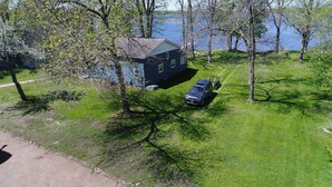 A house with a lawn and a body of water in the background. - Sunset Harbor Retreat,3 bed, 2 bath w/ private launch and dock in charming Isle (Isle)
