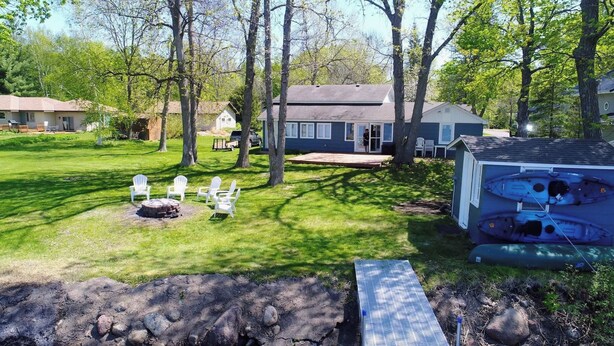A backyard with a fire pit, white chairs, and a boat shed. - Sunset Harbor Retreat,3 bed, 2 bath w/ private launch and dock in charming Isle (Isle)
