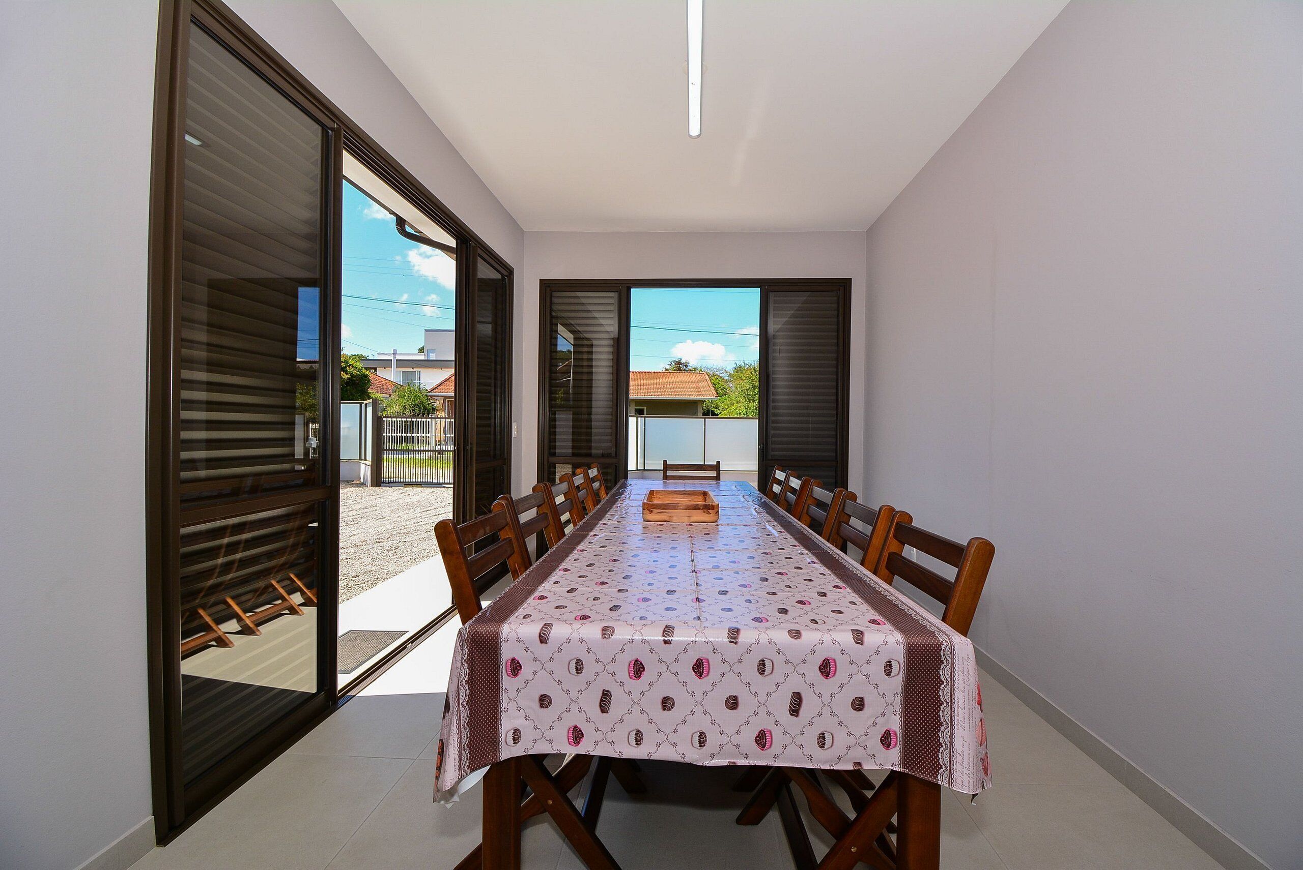 Uma sala de jantar com mesa posta para seis pessoas, uma porta de vidro deslizante e vista para o exterior.