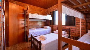 A room with two single beds, a wooden floor, brick walls, and a wooden ceiling. - Casa no Campeche a 300m do Mar - SDI019 (Florianópolis)