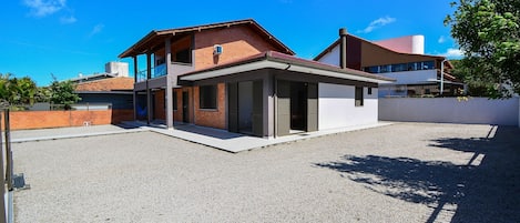 Una casa moderna de dos pisos con un porche cubierto, fachada de ladrillo y techo plano.