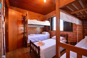 Ein Zimmer mit zwei Einzelbetten, Holzboden, Backsteinwänden und Holzbalkendecke.