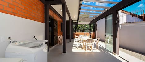 A laundry area with a washing machine, a dryer, and a water heater. There is a patio with outdoor furniture and a glass door leading to a garden.