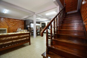 A staircase with wooden railings, a brick wall, and a sofa in a room with a tiled floor.