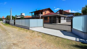 A residential area with houses, a gated entrance, and a clear sky. - Casa no Campeche a 300m do Mar - SDI019 (Florianópolis)