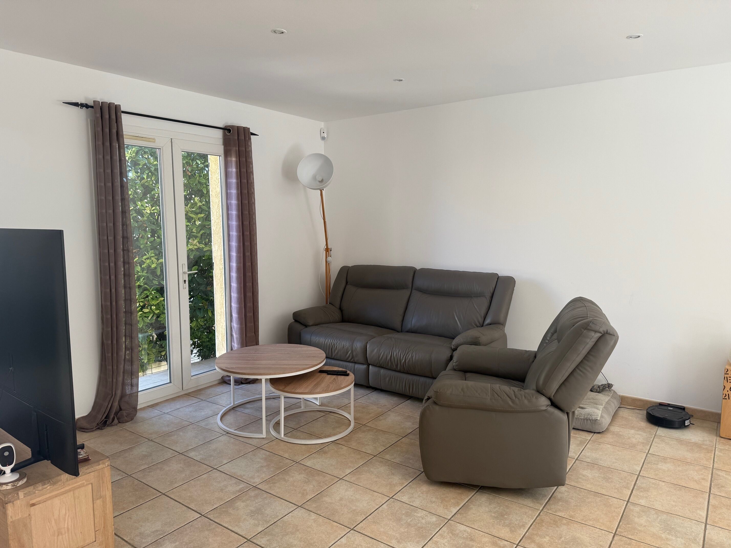 A living room with a sofa, a coffee table, a TV, and a lamp.