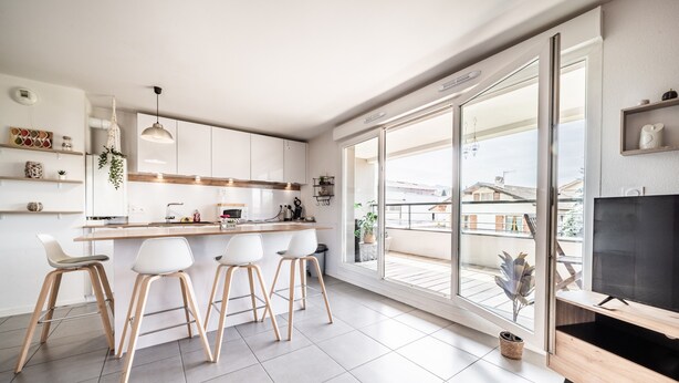 A modern kitchen with a bar area, large windows, and a TV. - Apartment "Le Cocon" with Mountain View, Balcony, and Wi-Fi (Thonon-les-Bains)