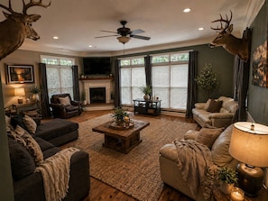 A living room with a fireplace, leather sofas, a coffee table, and deer antlers on the walls.