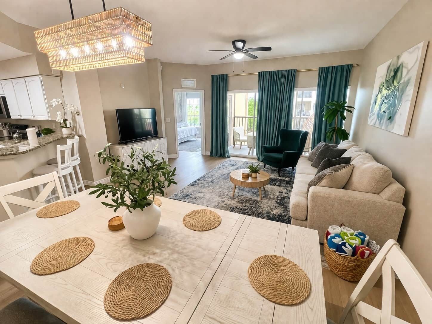 Un salon moderne avec un canapé, un téléviseur, une table à manger avec des sets de table et un ventilateur de plafond.