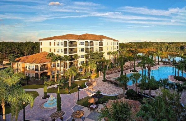 Ein Resort mit einem großen Gebäude, einem Schwimmbad und angelegten Grünflächen.