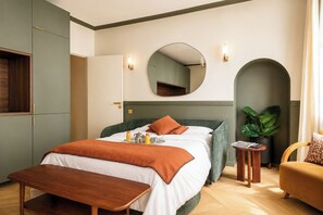 Ein Hotelzimmer mit Bett, Nachttisch, Spiegel und einer Zimmerpflanze.