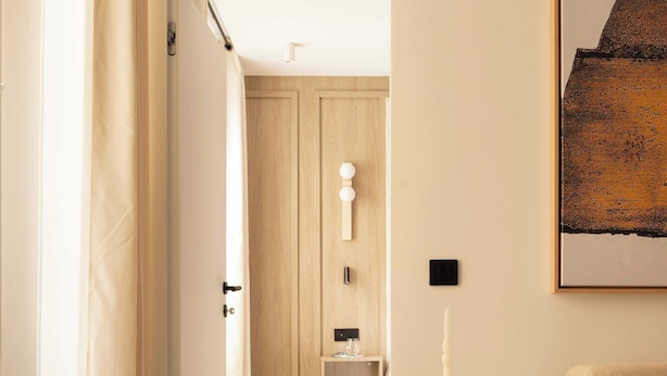 A room with a wooden floor, a round side table with a candle, a sofa, and a painting on the wall. - Modern Apartment a/c 1ch/4p - Saint -germain (Paris)