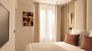 A hotel room with a bed, curtains, a painting, and a wall-mounted light fixture. - Modern Apartment a/c 1ch/4p - Saint -germain (Paris)