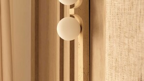 A wall-mounted light fixture with two spherical bulbs, a wooden panel, and a textured fabric backdrop. - Modern Apartment a/c 1ch/4p - Saint -germain (Paris)