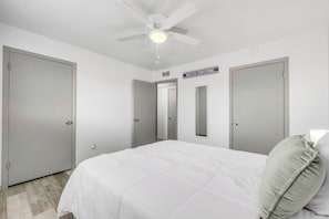 Quarto com uma cama, um ventilador de teto e duas portas.