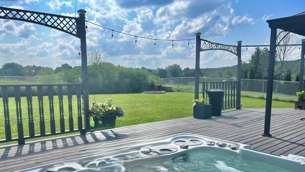 Ett bubbelbad på ett trädäck med en pergola och ljusslingor.