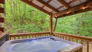 Un jacuzzi con terraza de madera y vista a un bosque.