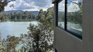 A lake with trees and mountains in the background, viewed from a window. - Charming 1-bedroom apartment in soothing Guatapé perfect for getaway (Guatapé)