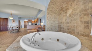Ein geräumiges Badezimmer mit einer großen Badewanne, einer separaten Duschkabine und einer Küche im Hintergrund.