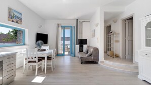 Un interior moderno con comedor, sofá, televisor y vista a través de una puerta.