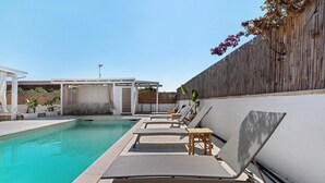 Una piscina con sillones de descanso y una pérgola.