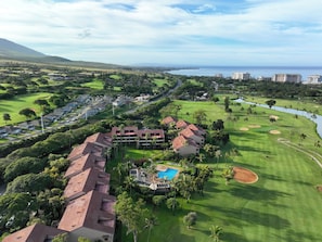 Ein Golfplatz mit Pool, umgeben von Wohngebäuden und Blick auf den Ozean.