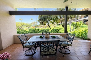 An outdoor patio with a table and chairs, a view of a landscaped garden, and a building in the background. - NEW Kaanapali Royal Large Ground Floor 2-Bedroom Condo with Complimentary Rental Car with 6+ Nights! KRO-F102 by KBM (Lahaina)
