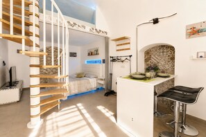 Un interior moderno con una escalera espiral, una zona de cocina con taburetes de bar y una mesa de comedor.