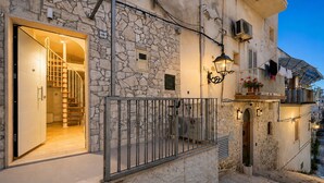 A stone building with a spiral staircase leading to an interior room, a balcony with a railing, and a street view. - Apartment 'Venti Nodi' with Balcony, Wi-Fi and Air Conditioning (Vieste)