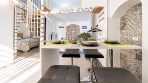 A modern kitchen with a central island, a spiral staircase, and a stone accent wall. - Apartment 'Venti Nodi' with Balcony, Wi-Fi and Air Conditioning (Vieste)