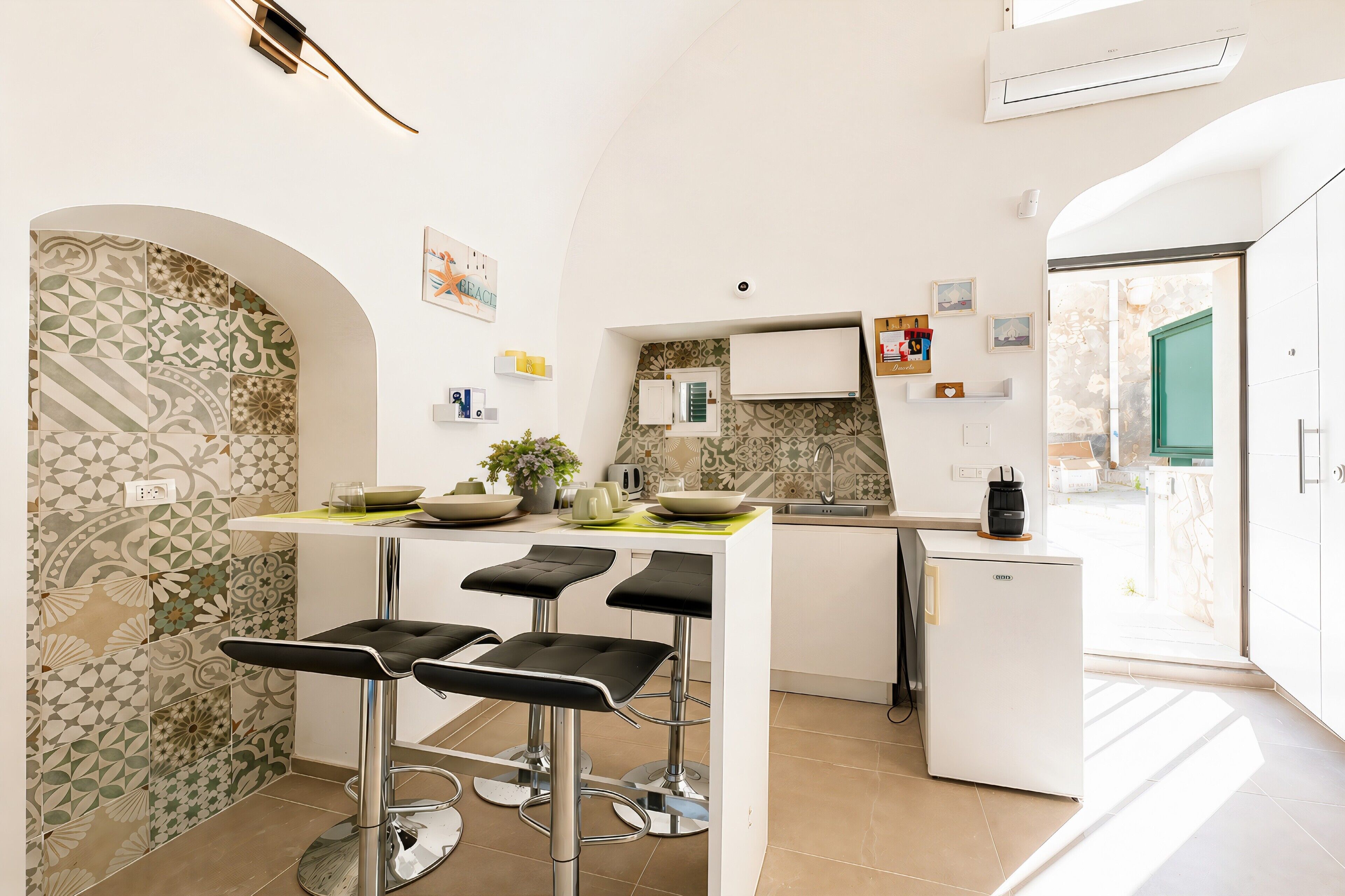 A modern kitchen with bar stools, a refrigerator, and a window.