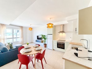 Ein modernes Apartment mit Essbereich, Küche, Wohnzimmer und einem großen Fenster.