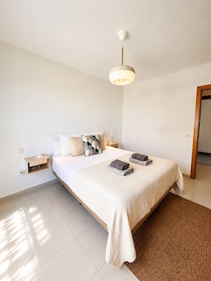 Ein Schlafzimmer mit einem großen Bett, Nachttischen, einer Hängelampe und einer Tür.