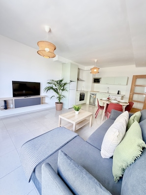 Ein modernes Wohnzimmer mit einer Couch, Fernseher und Essbereich.