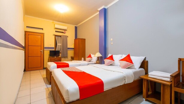 Une chambre d’hôtel avec un grand lit, une télévision, une armoire en bois et une salle de bain avec un rideau de douche.