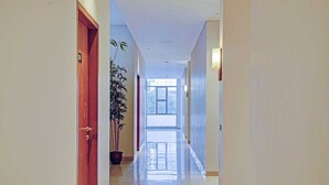 A hotel hallway with a wooden door, a potted plant, and a view of the outdoors. - Luxury Deluxe DBL Retreat W/ Free WiFi and Parking (Bandung)