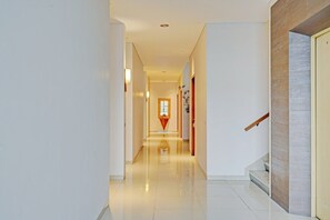 Ein moderner Hotelgang mit glänzendem Boden, einer Treppe und einer Tür mit einer Holzhandläufe.
