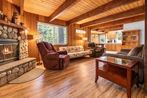 A cozy living room with a stone fireplace, wooden ceiling beams, and a comfortable seating area. - Teacher's Dream (Big Bear Lake)
