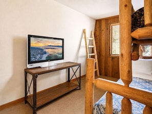 A room with a television on a wooden table, a wooden ladder, and a bunk bed with a patterned mattress. - Teacher's Dream (Big Bear Lake)