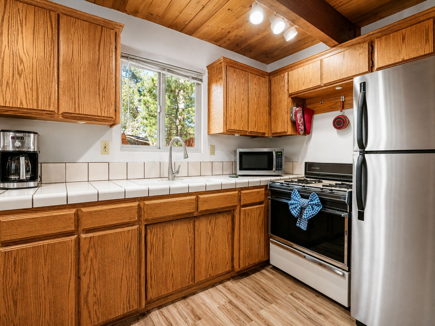 Una cocina con gabinetes de madera, un refrigerador de acero inoxidable, un microondas y una estufa.