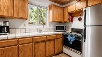 Una cocina con gabinetes de madera, un refrigerador de acero inoxidable, un microondas y una estufa.